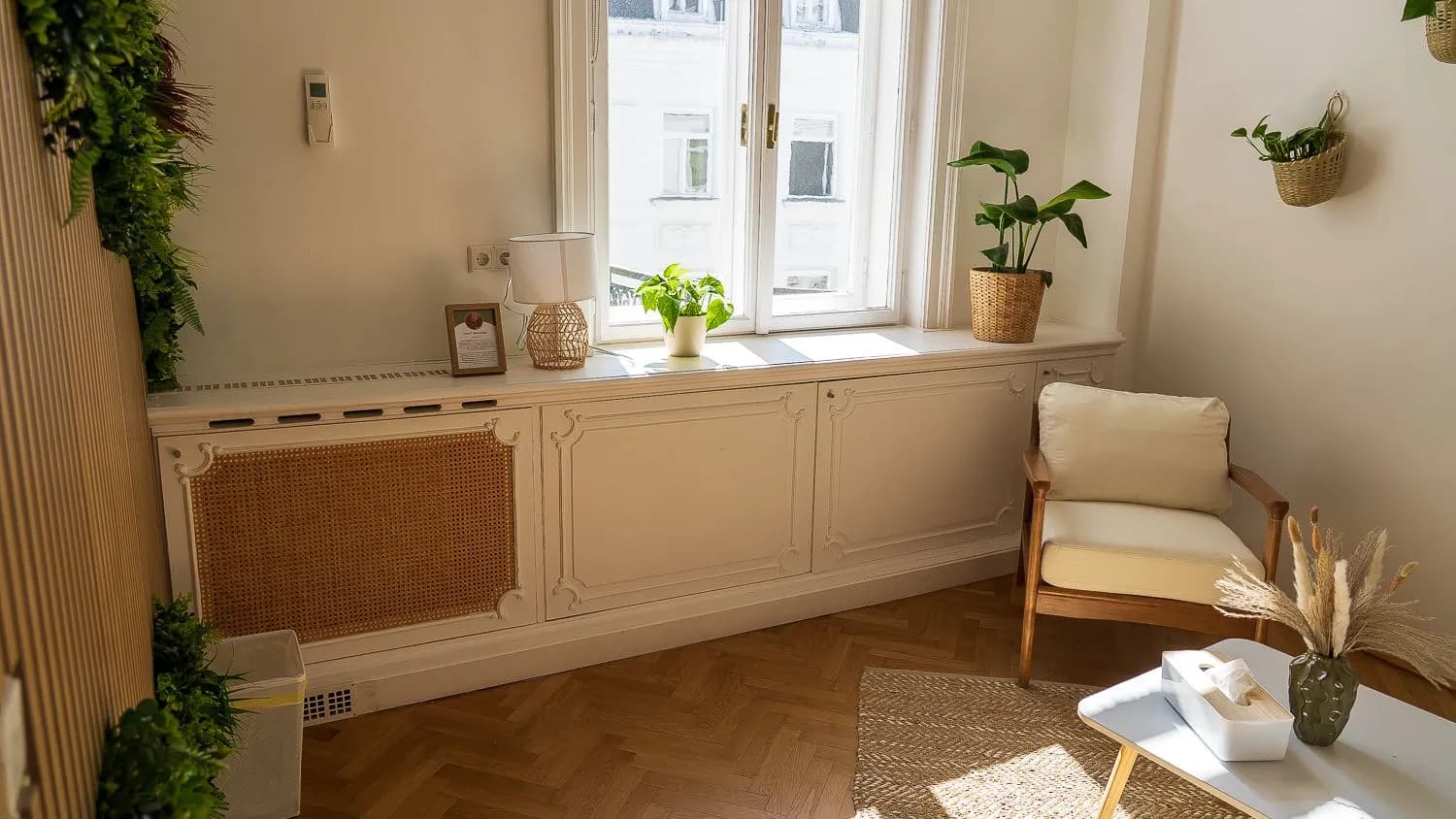 Altbaufenster mit Pflanzen auf der Fensterbank, daneben ein heller Sessel.